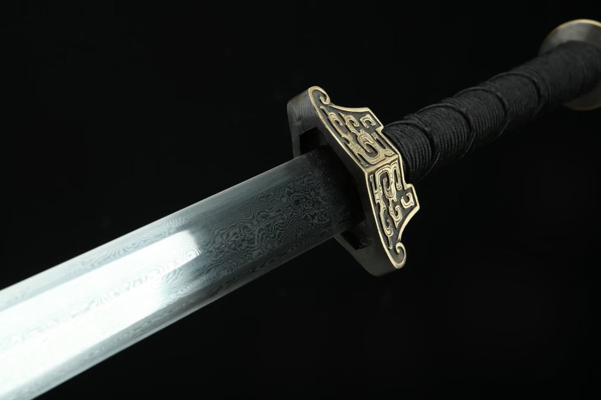 Close-up of the Hanwang Jian patterned steel blade, brass guard and black cord-wrapped handle