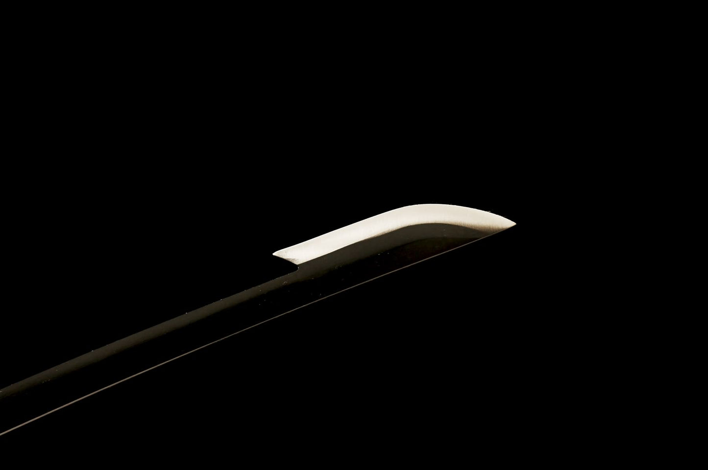 Baked-black katana blade tip with contrasting polished edge area