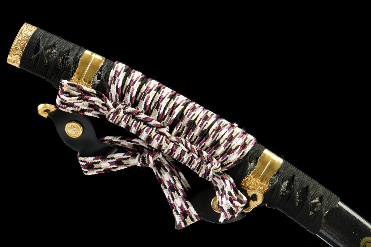 Japanese-style Tachi black scabbard and multicolored braided cord beside the wrapped handle