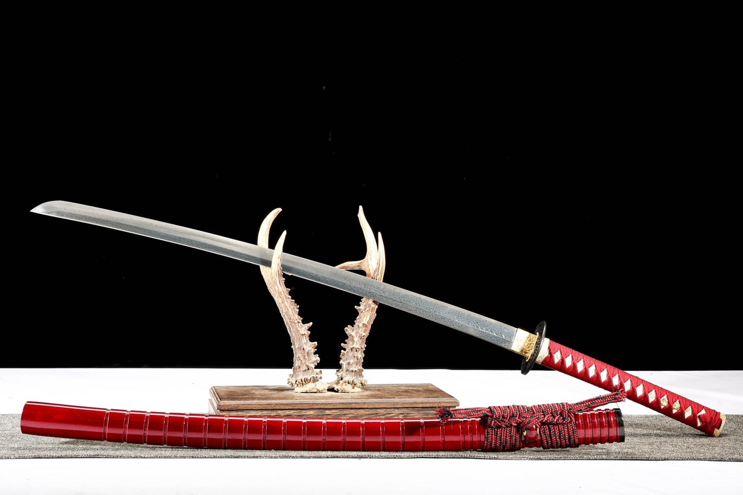 Feather-pattern katana displayed with red lacquer wood saya