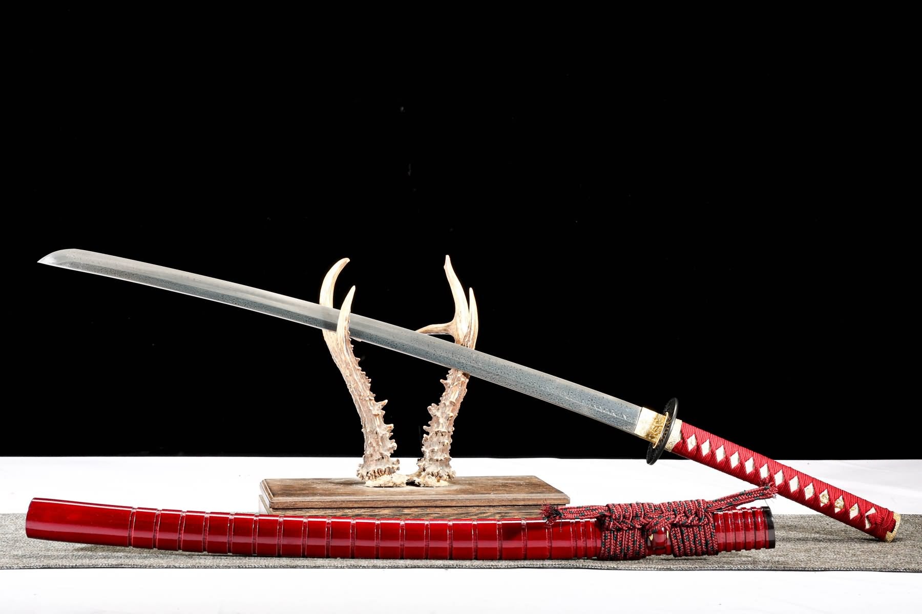 Feather-pattern katana displayed with red lacquer wood saya