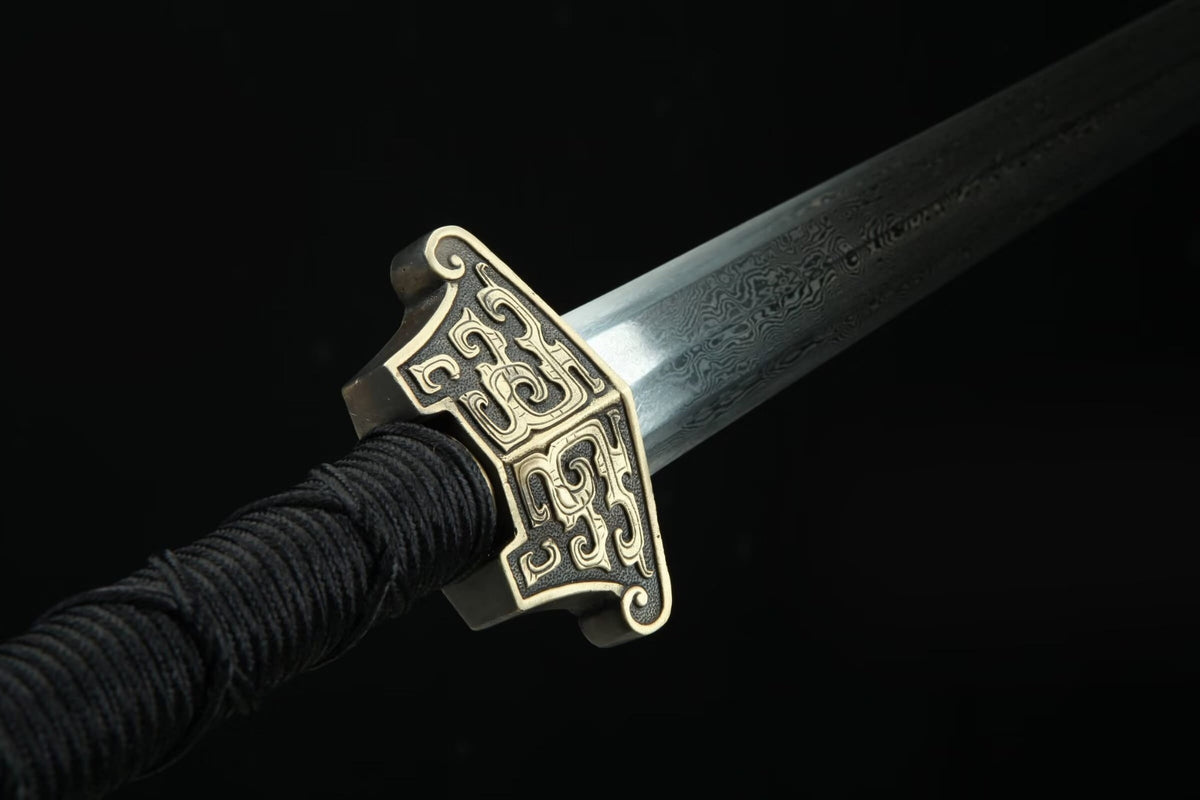 Reverse close-up of the carved brass guard and patterned steel blade on the Hanwang Jian
