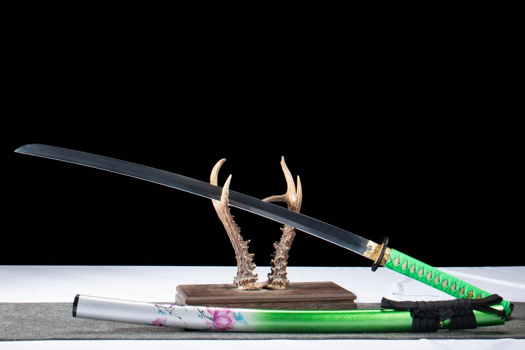Black-finished katana blade displayed above green lotus scabbard